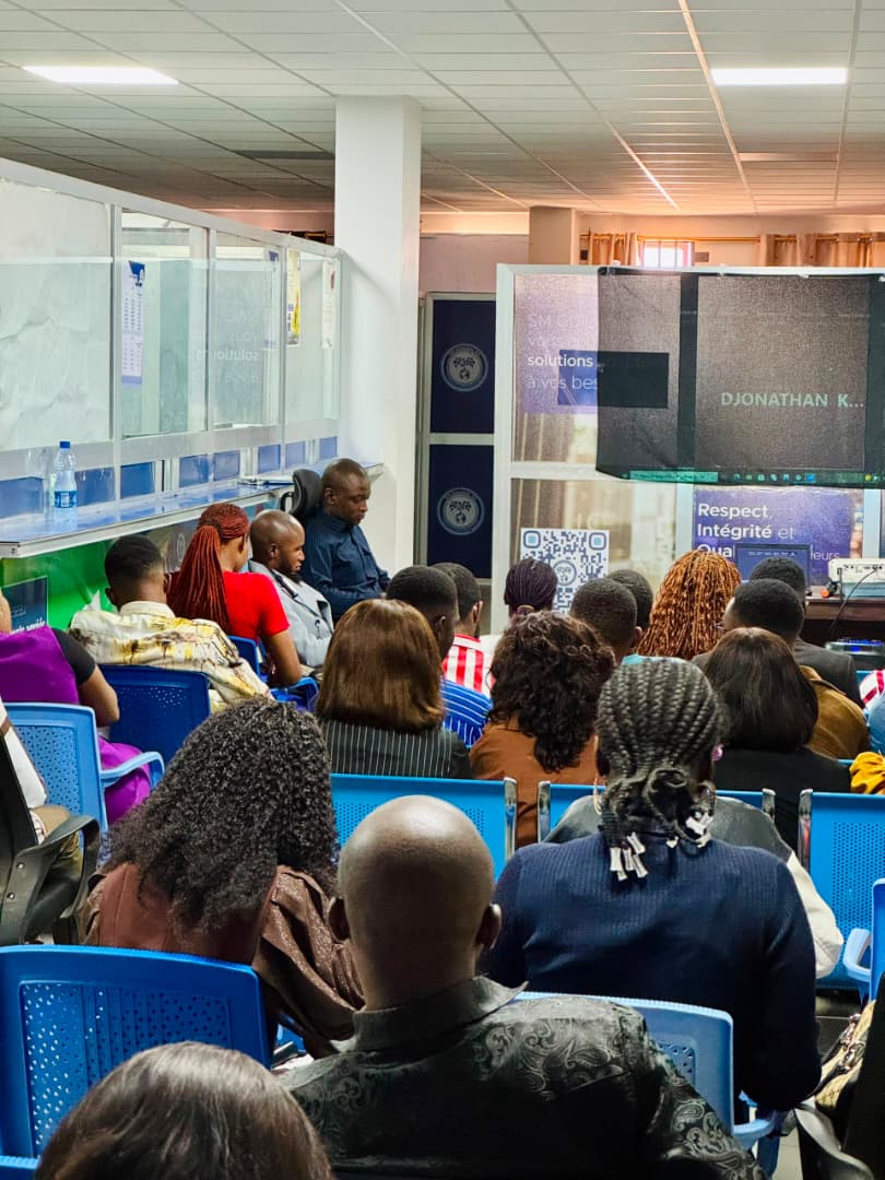 Photo des agents assis entrain de suivre le culte d'évaluation en visioconférence à l'agence Guilgal de Lubumbashi