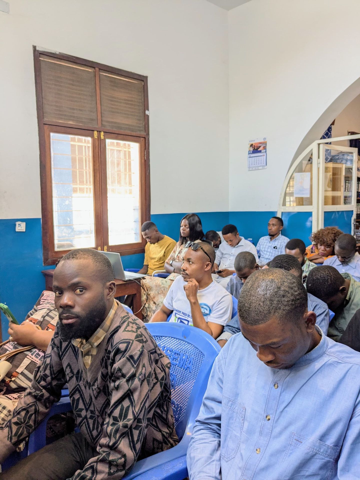 Photo des agents assis entrain de suivre le culte d'évaluation en visioconférence à l'agence Guilgal de Kalemie